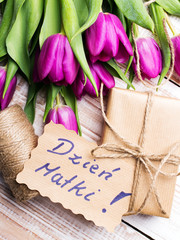 Mother's Day card and a bouquet of beautiful tulips on wooden background, with Polish words 