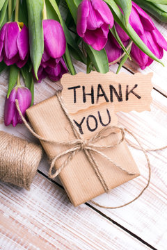 "Thank you" card, gift box and tulip bouquet on white wooden background