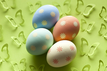 Four colored Easter eggs in pastel color on green background