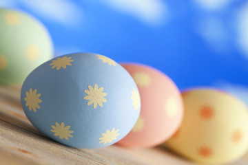 Easter eggs in pastel color on wooden table and sky background