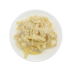 Top view of a plate of fettuccine alfredo isolated on a white background.