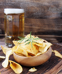 Chips in a wooden bowl and beer