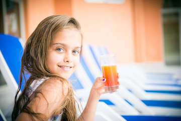 girl drinking juice on a deck chair. beautiful girl with a glass of juice. vitamin deficiency and healthy food for children
