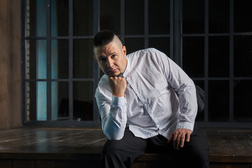 Portrait of young man, black slacks and white shirt, hairstyle with shaved temples and slicked back hair at the head, emotions, black window, Brick wall, beard, skinhead, brutal, evil, killer