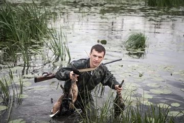 Crédence de cuisine en verre imprimé Chasser Hunter man with proie après une chasse réussie à travers les zones humides