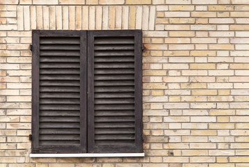 Old window with wooden shutters in brick wall