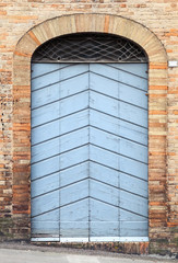 Blue wooden door with arch in old stone wall