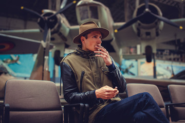 A man in a hat smoking cigarette on airplanes exhibition.