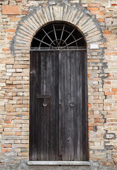 Black wooden door with arch in old stone wall