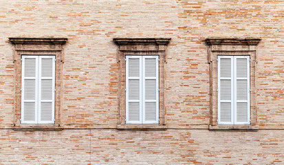 Three windows with white closed wooden shutters