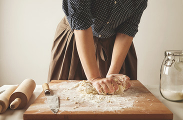 Woman kneads dough for pasta on wooden board