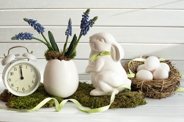 Easter decoration with white rabbit, spring flowers, alarm clock and rural eggs. Easter bunny. Easter background.  © greenazya