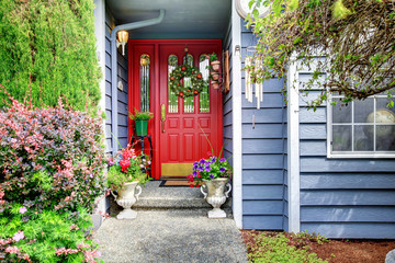 Fototapeta na wymiar Bright front red door to blue American home with floral exterior