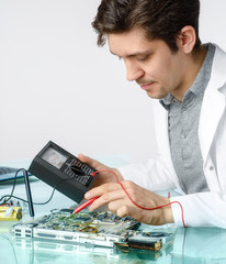 Young energetic male tech or engineer repairs electronic equipme