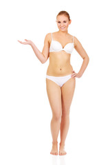 Happy woman in white lingerie presenting something on open palm