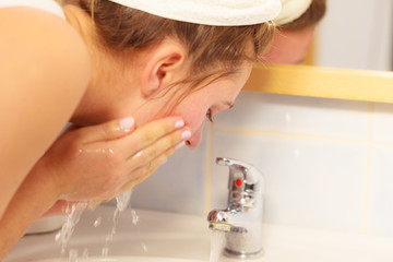 Woman washing face in bathroom. Hygiene