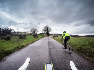 couple of cyclists in an uphill road during a storm. POV Original point of view
