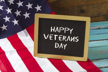 Fototapeta na wymiar veterans day chalk sign on blue wood background with flag