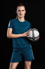 Smiling female football player with ball isolated on black backg