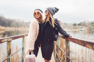 Outdoor lifestyle portrait of two best friends, smiling and having fun together, enjoy each other company posing and making selfie pictures to each other and share happiness

