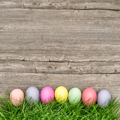 Easter eggs in green grass on wooden background