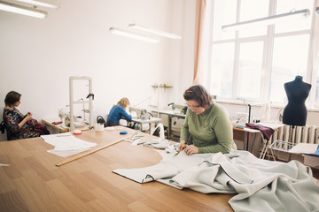 dressmaker working on the shop floor with the fabric scissors