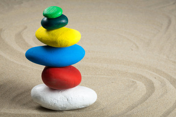 Fototapeta na wymiar Cairn faits de galets de différentes couleurs dans le sable