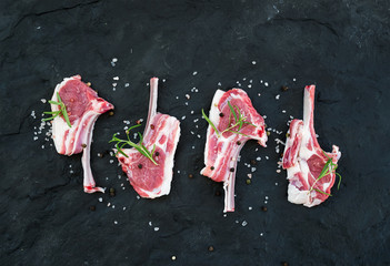 Raw lamb chops. Rack of Lamb with rosemary and spices over dark slate stone background. © sonyakamoz