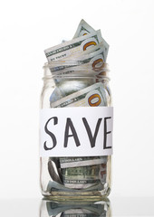 money in a glass jar with 100 dollars bill in it and text save 
