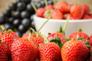 Fresh strawberry in the bowl on wooden background