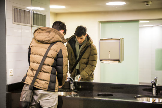 Reflection of man washing hands in bathroom