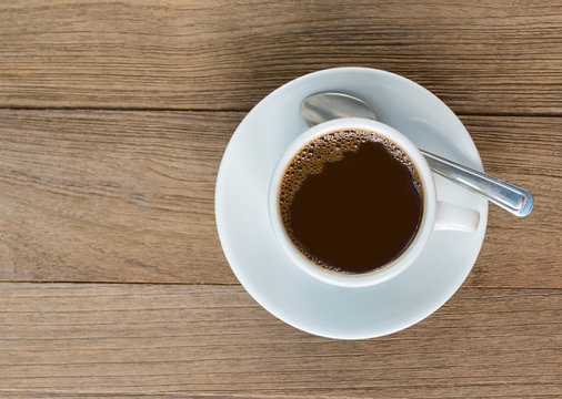 Cup of coffee on wooden table, top view