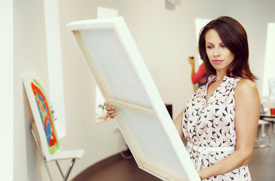 Young caucasian woman standing in art gallery front of  paintings