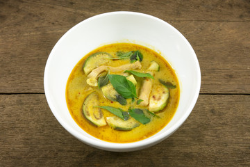 The delicious homemade Thai green curry with pork (Gang Keaw Wan) in white bowl on old wooden planks.