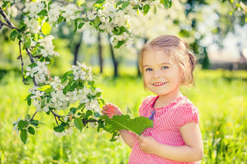 Happy little girl playing in spring apple tree garden
