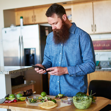 Bearded Man Following Recipe On Tablet To Make Street Tacos