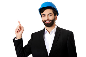 Engineer in protective helmet pointing up.