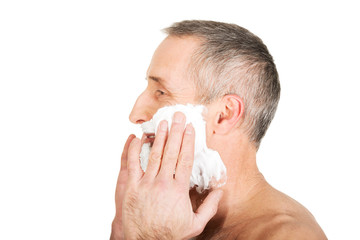 Naklejka premium Mature man applying shaving foam