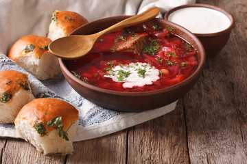 Ukrainian borscht red soup with garlic buns on the table. horizontal
