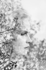 Creative portrait of beautiful young woman made from double exposure effect using photo of trees, leaves and nature, monochrome toned