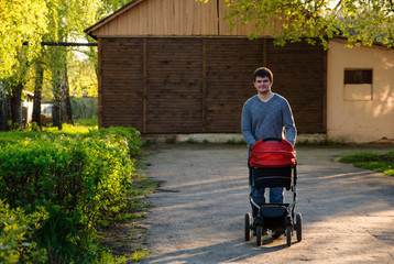Obraz premium A man walking with a baby stroller on green street