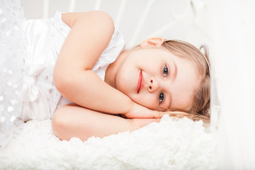 Obraz na płótnie Canvas Cute little girl in white pretending sleep