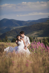 Romantic fairytale couple newlyweds kissing and embracing on a background of mountains 