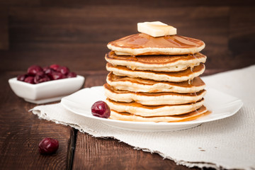pancakes with cherry and butter on a dark background