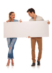 handsome couple holding a blank white sign