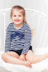 Fototapeta premium Happy little girl in striped shirt on white background