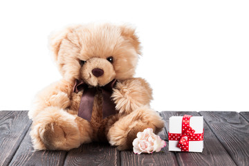 Teddy bear and gift box on wood