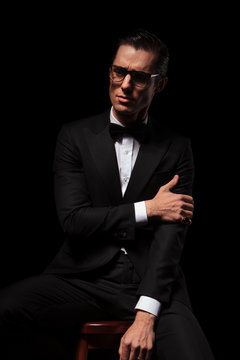 classy man in black wearing glasses posing in dark studio