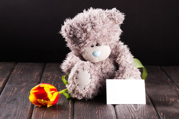 Teddy bear and roses with card on wood