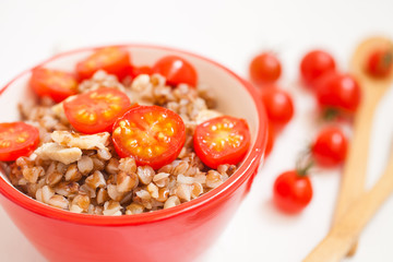 buckwheat cereal with tomatoes in a bowl on a table, selective focus